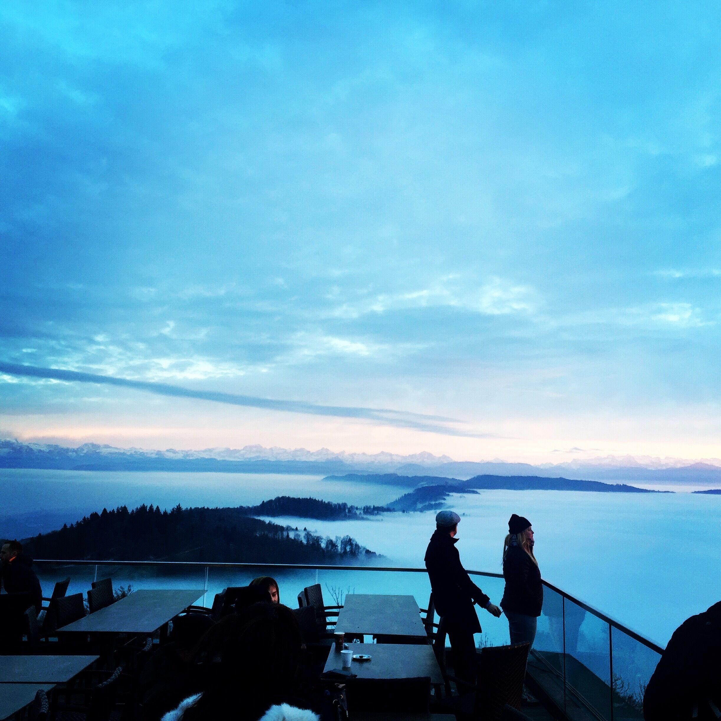A scenic overlook with a view of a lake and distant mountains.