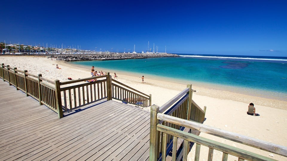 Una passerella in legno conduce a una spiaggia sabbiosa con acque cristalline.