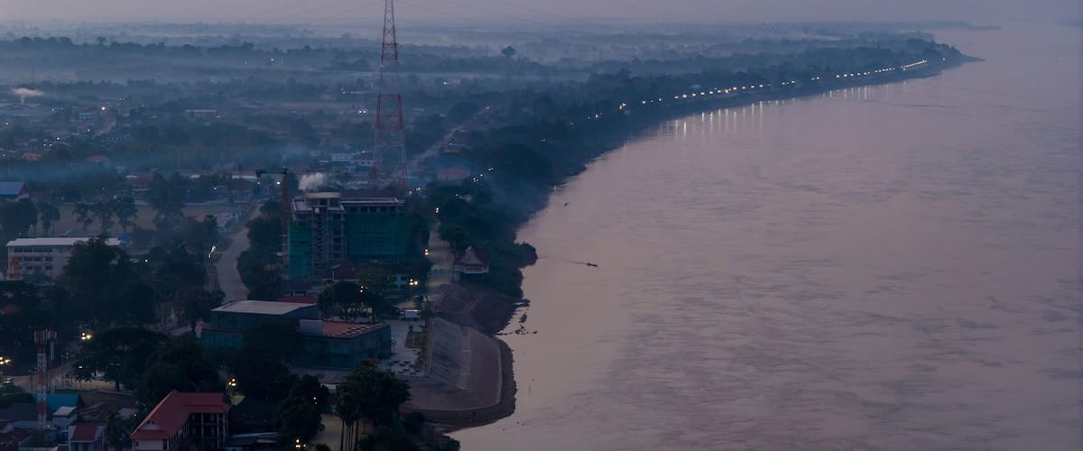 Blue hour aerial photography of Savannakhet. The deep blue sky contrasts with the warm artificial lights of the city, creating a moody atmosphere.
