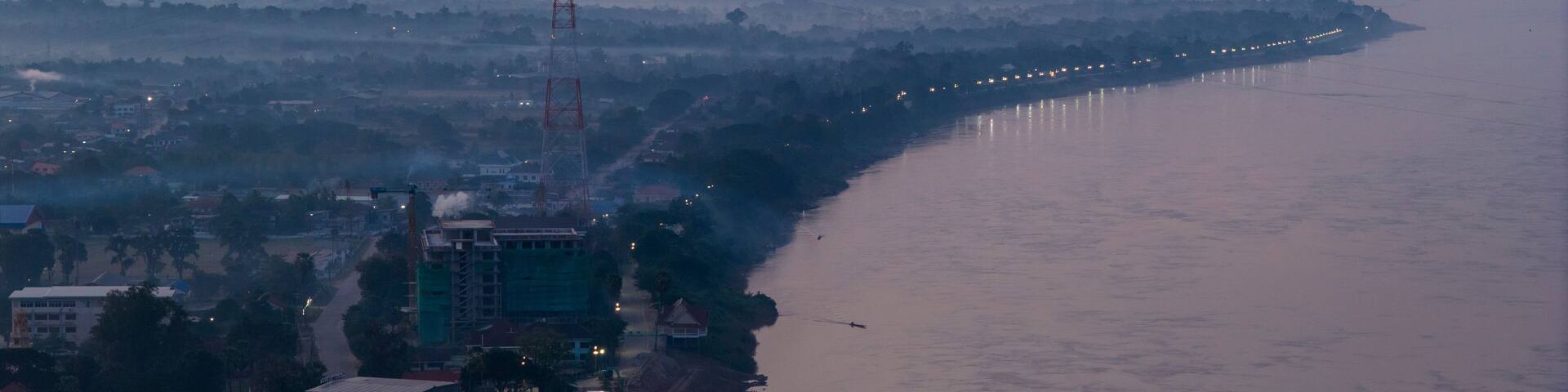 Blue hour aerial photography of Savannakhet. The deep blue sky contrasts with the warm artificial lights of the city, creating a moody atmosphere.
