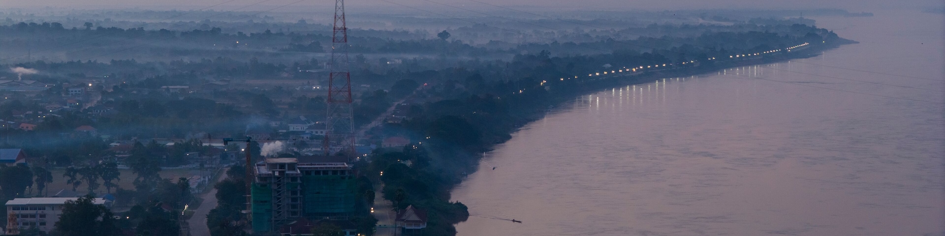 Blue hour aerial photography of Savannakhet. The deep blue sky contrasts with the warm artificial lights of the city, creating a moody atmosphere.
