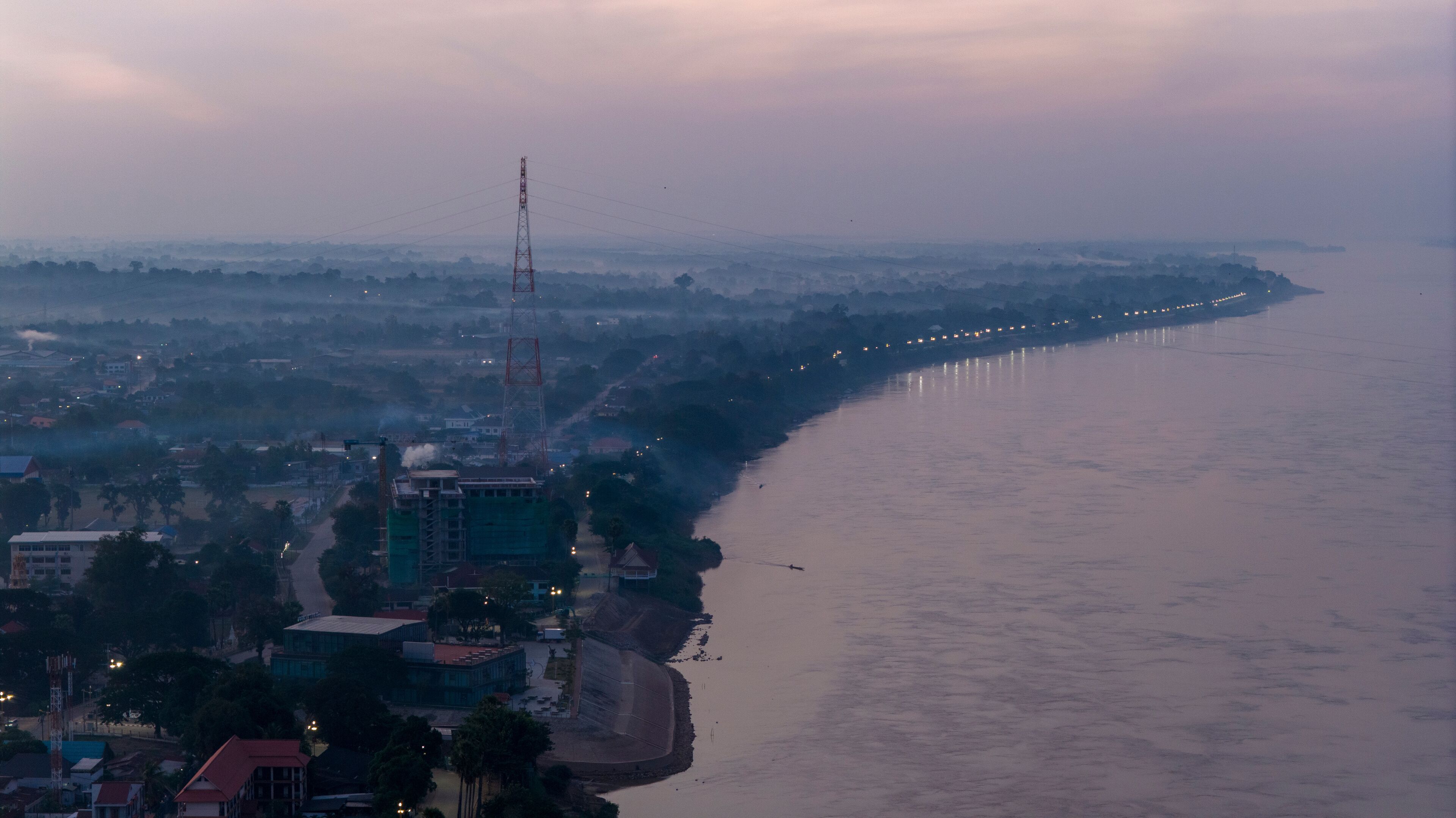 A coastal cityscape with a prominent tower, a river, and a distant shoreline.