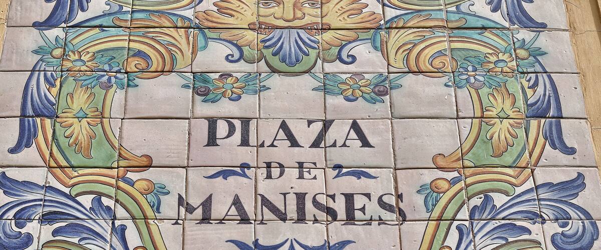 A tiled wall with 'PLAZA DE MANISES' written in the center.