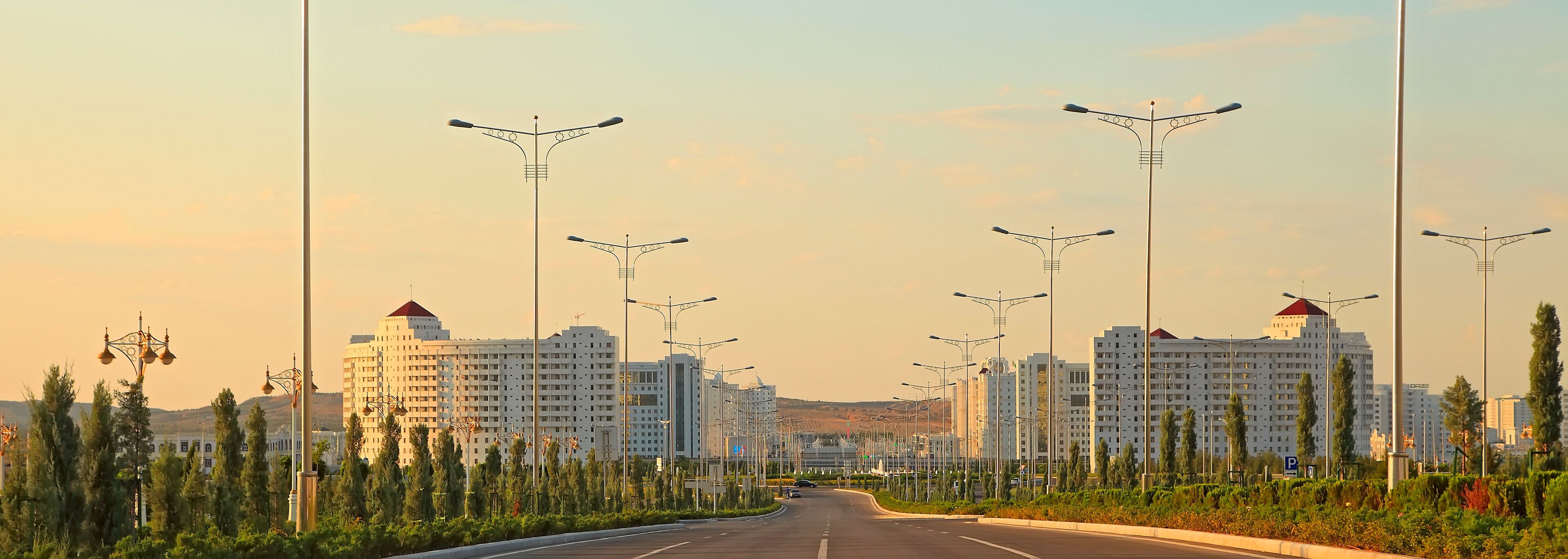 A wide, straight road lined with modern streetlights and tall residential buildings.