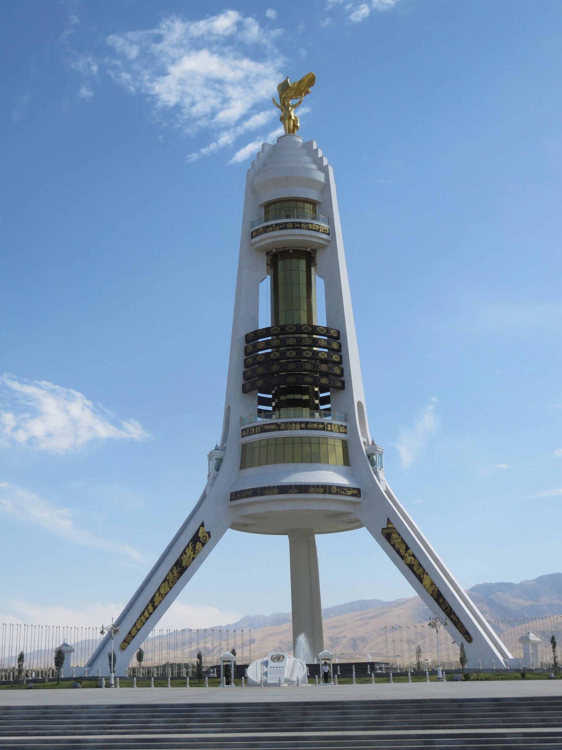 You can see the golden statue of the first president presiding over his children atop the Arch of Neutrality. He is facing the city of Ashgabat, while behind him are the mountains separating Turkmenistan from Iran. The arch of Neutrality confirms Turkmenistan&#x27;s decision to stay neutral in any conflicts after they left the Soviet Union. You can take a ride up into the tower. Can you see the bottom lift on the right leg of the tower?