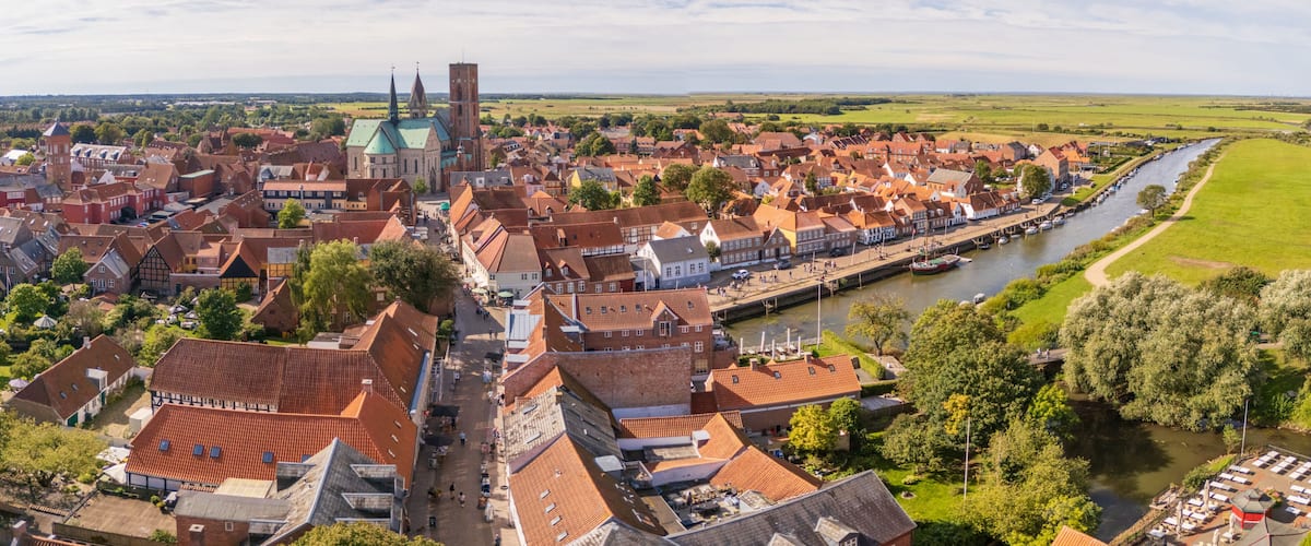 A town with a prominent church, a river, and surrounding greenery.