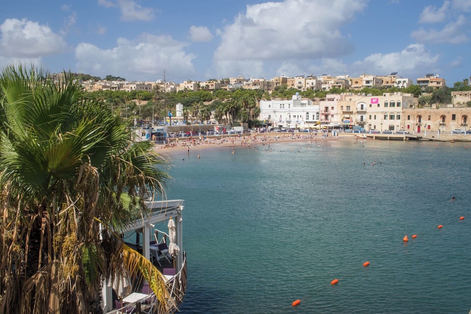 Una località costiera con spiaggia, palme e edifici.