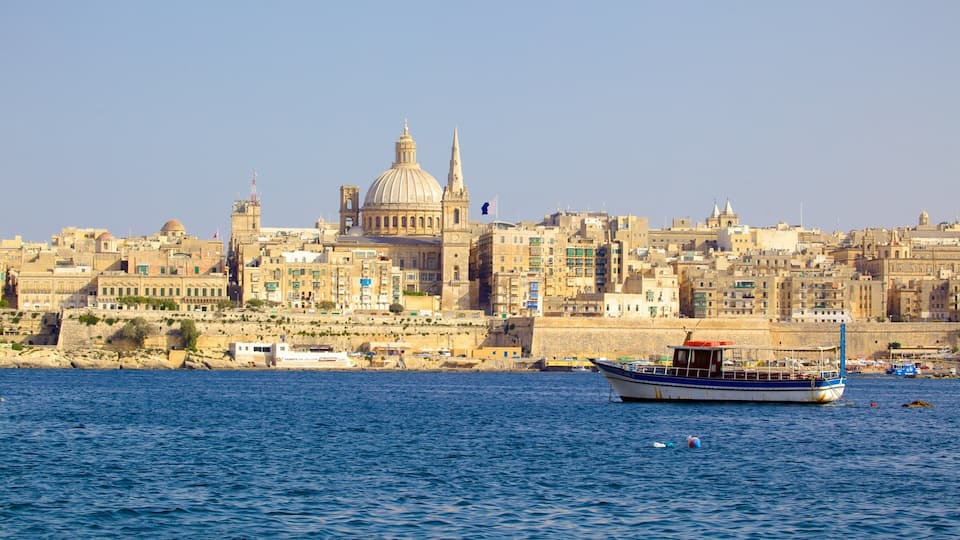 A coastal cityscape with historic buildings, a prominent dome, and a harbor with boats.