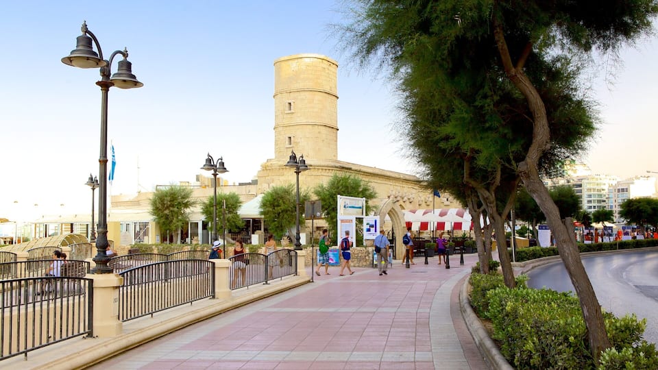 A historic tower, a paved walkway, and a street with pedestrians.