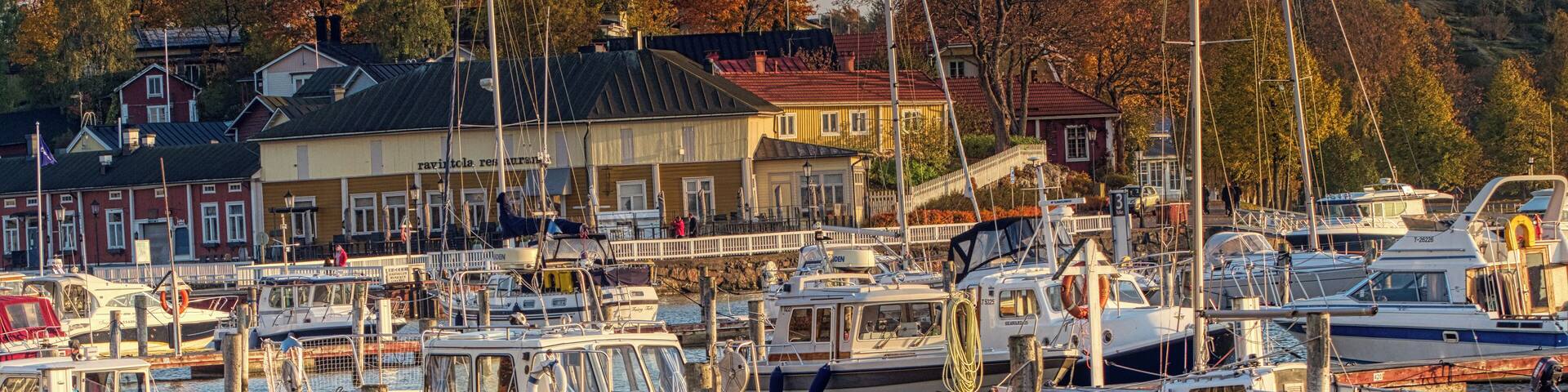 A marina with several boats docked, surrounded by buildings and trees.