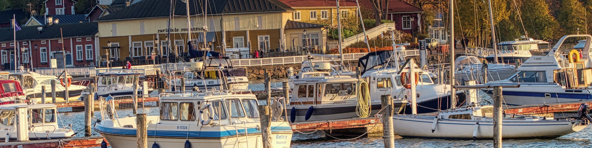 Un puerto deportivo con varias embarcaciones amarradas, rodeado de edificios y árboles.