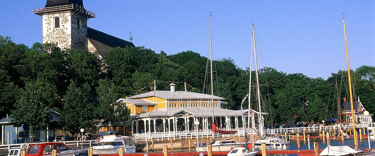 A marina with boats docked, a clock tower, and a building with a yellow facade.