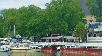 A waterfront with a clock tower, boats, and a pier with buildings.