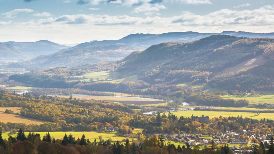 A valley with a river, a town, and surrounding hills.