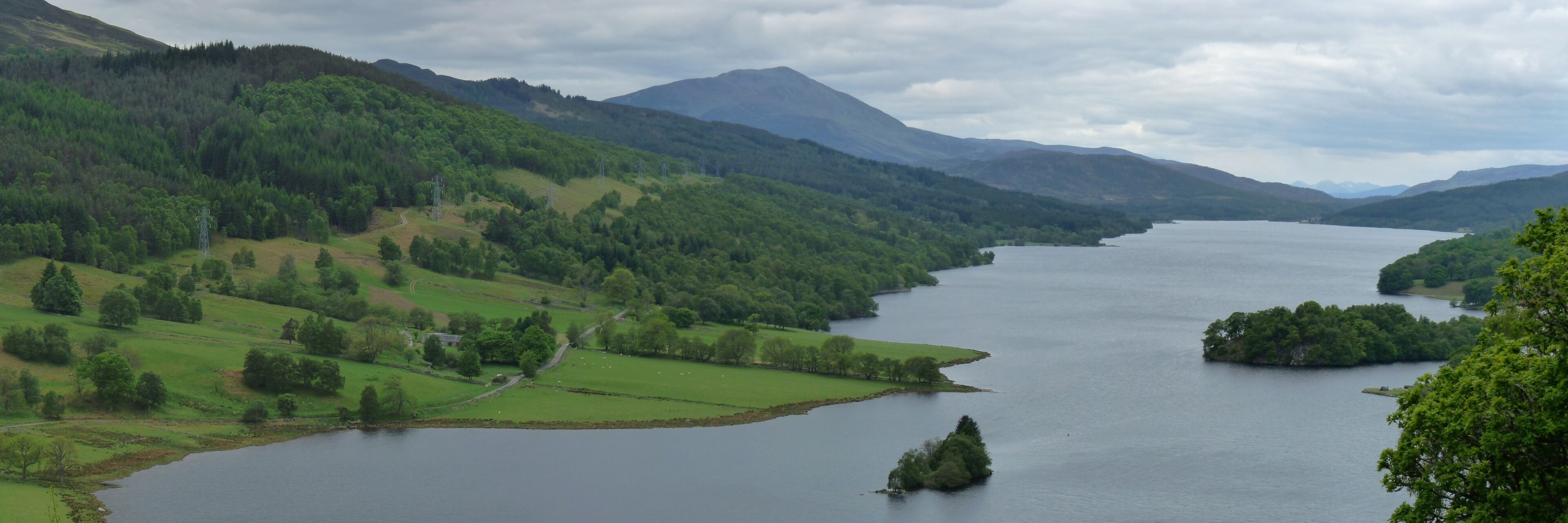 A lake surrounded by green hills and mountains.