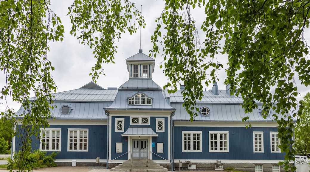 Sininen rakennus, jossa on valkoinen ovi ja ikkunat, ja sen ympärillä on puita.