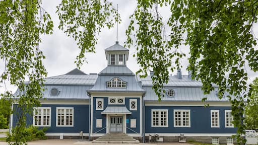 A blue building with a white door and windows, surrounded by trees.