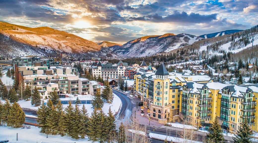 A snow-covered town with mountains in the background and a prominent yellow building in the center.