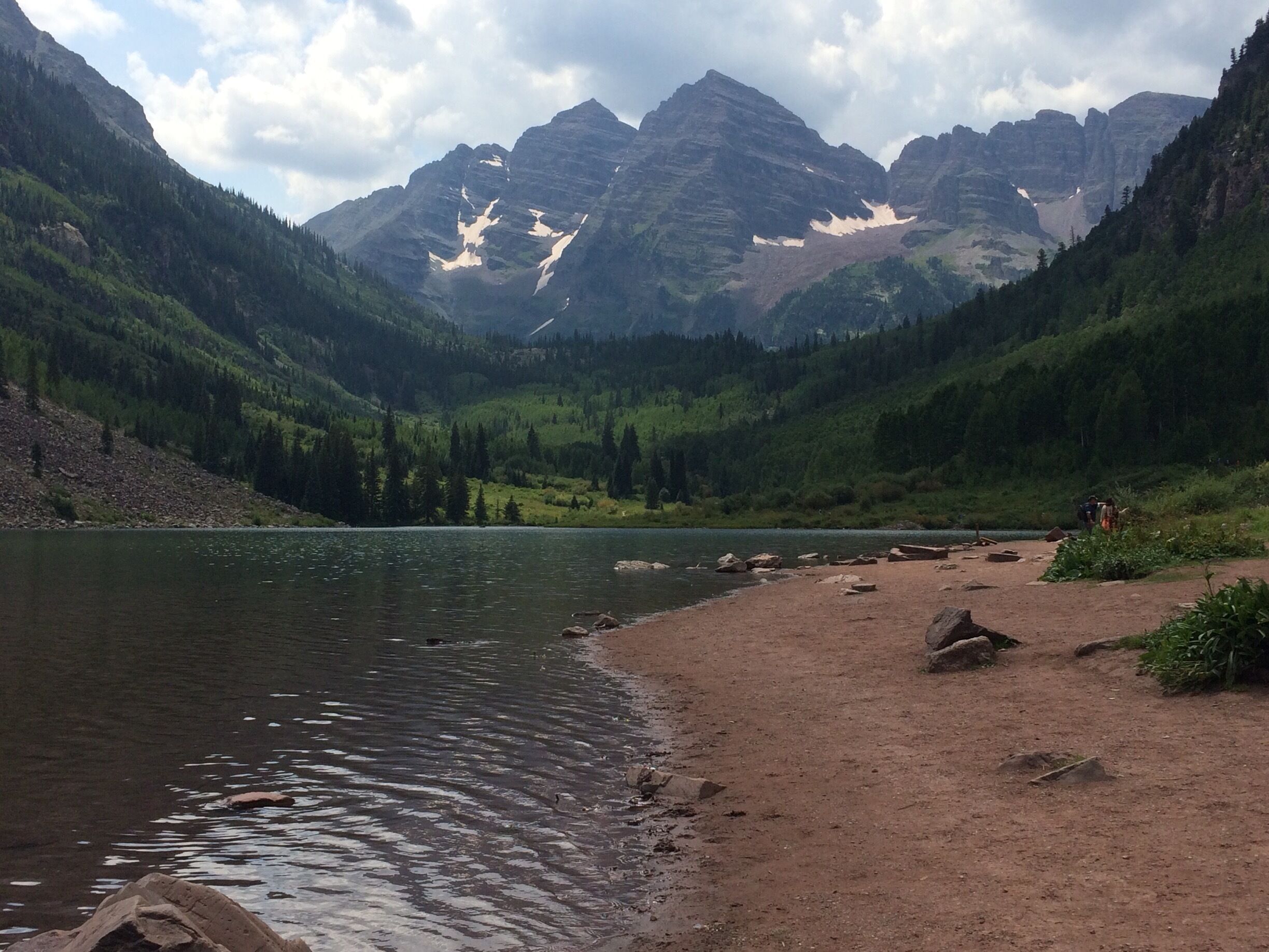 A mountain lake with a rocky shoreline and a forested valley.