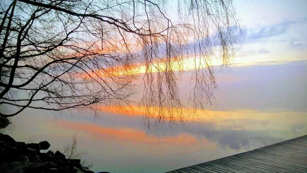 Une jetée en bois s’étendant sur une étendue d’eau calme, avec un coucher de soleil en arrière-plan.