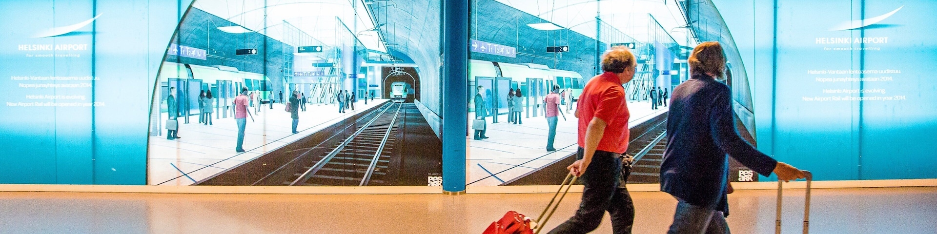 A modern indoor train station with a blue and white color scheme, featuring a large glass wall reflecting the interior.