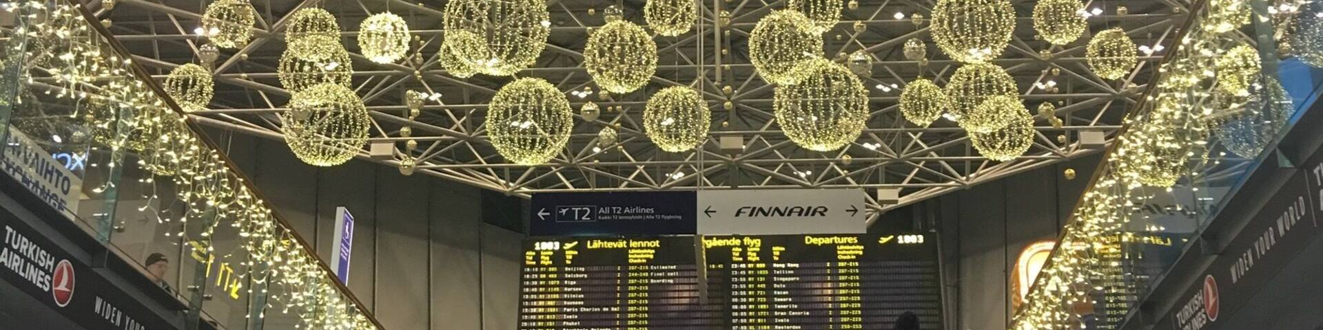 An airport terminal with escalators, heart-shaped lights on the ceiling, and signs for Turkish Airlines and Finnair.
