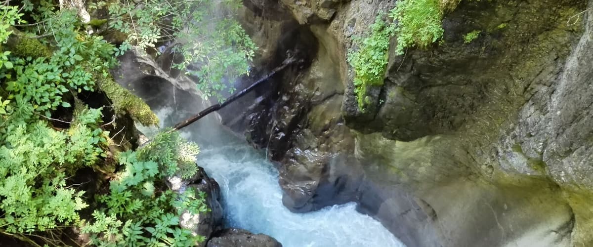A waterfall cascading over rocks surrounded by lush greenery.