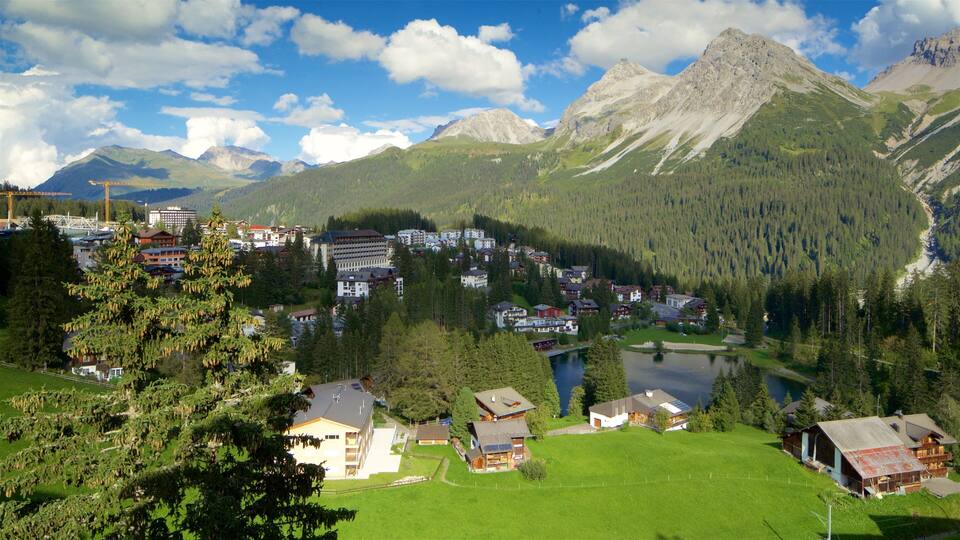 A mountainous village with a lake, surrounded by dense forests and towering peaks.