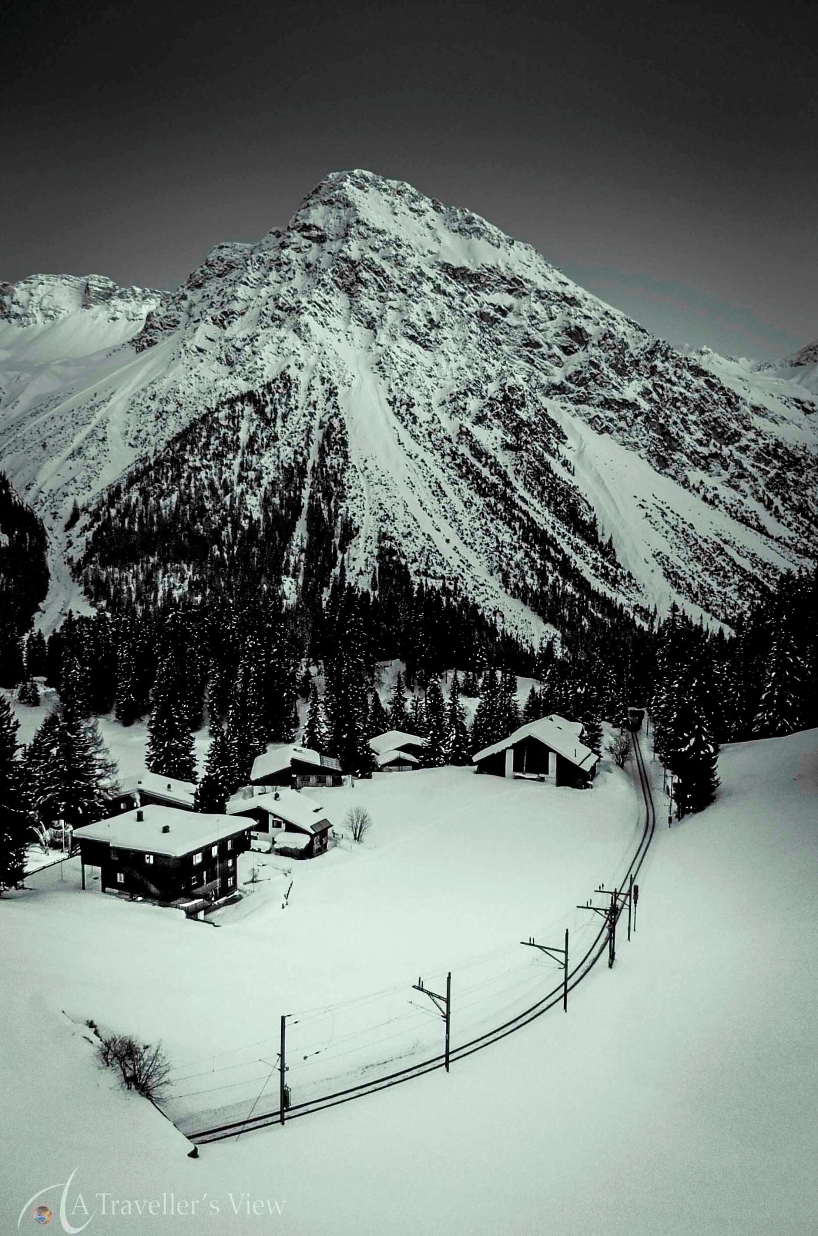 A snow-covered mountain with a cabin and a winding road.