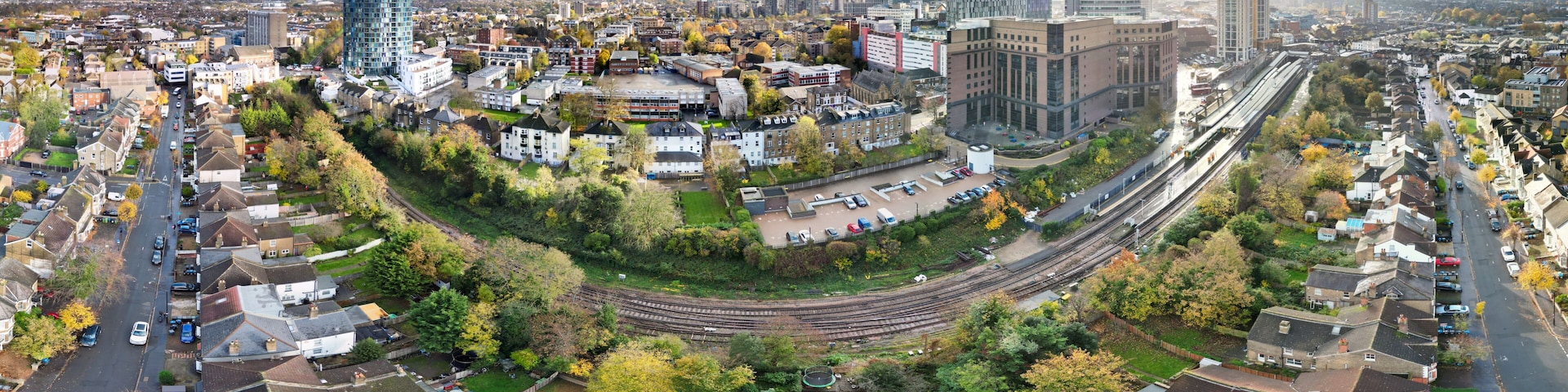 A cityscape with a prominent modern skyscraper, a curved railway track, and residential areas with houses.