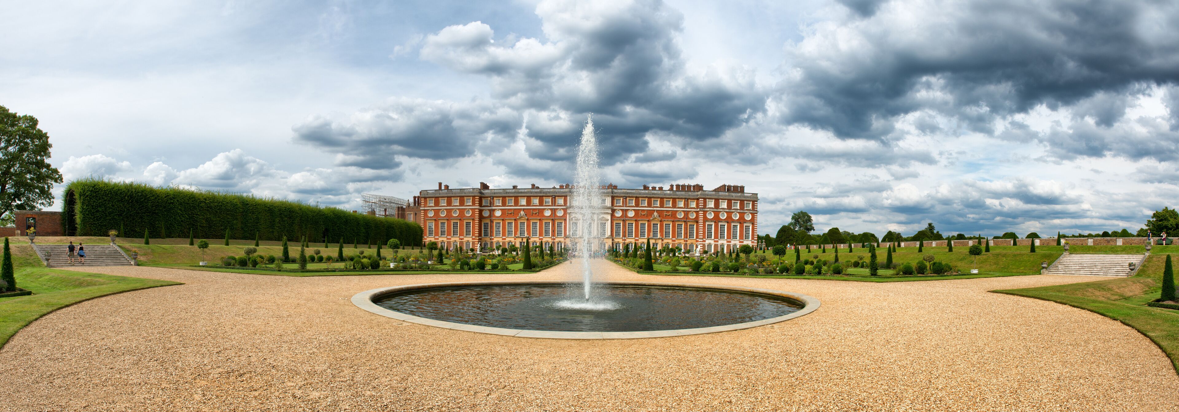 A large red building with a fountain in front.