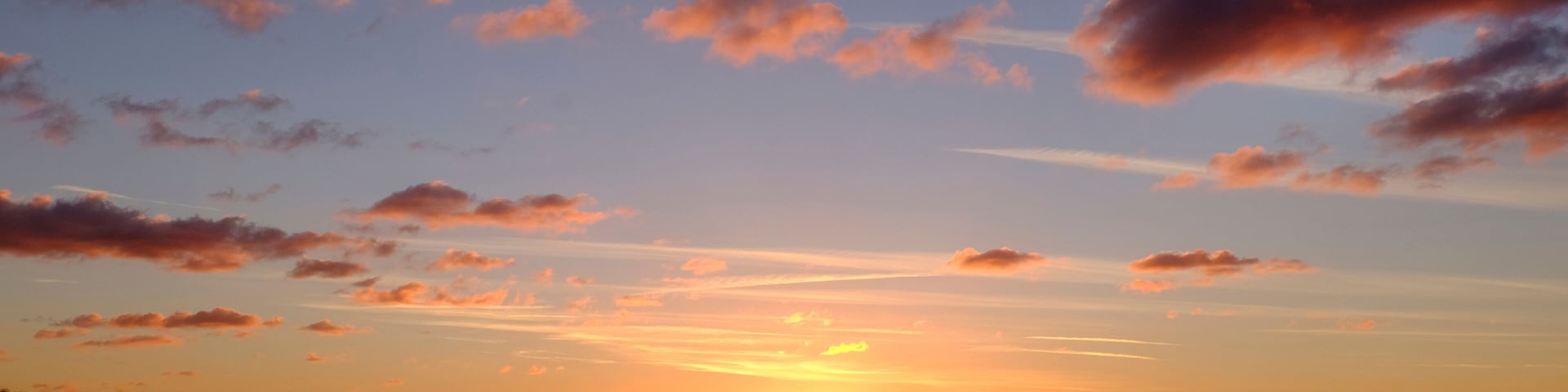 A sunset over a body of water with boats and a stadium in the background.