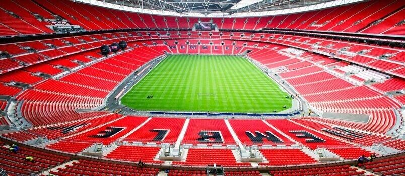 A stadium with red seating and a green field.
