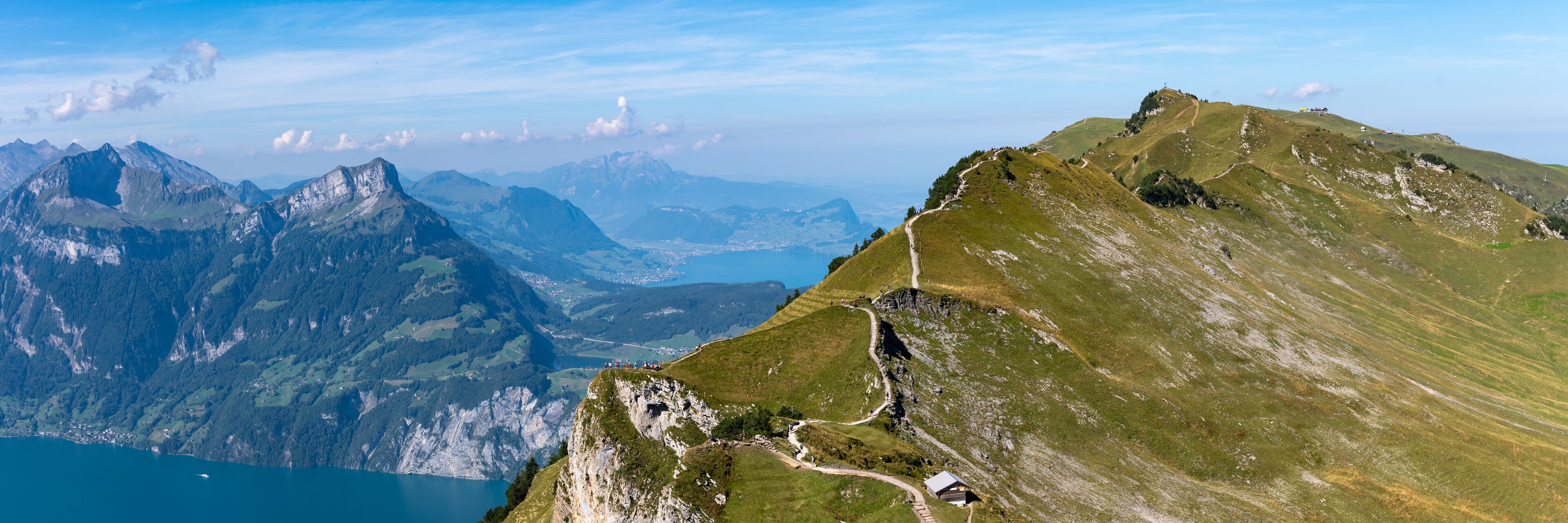 A mountain landscape with a clear sky, a lake, and a winding path.