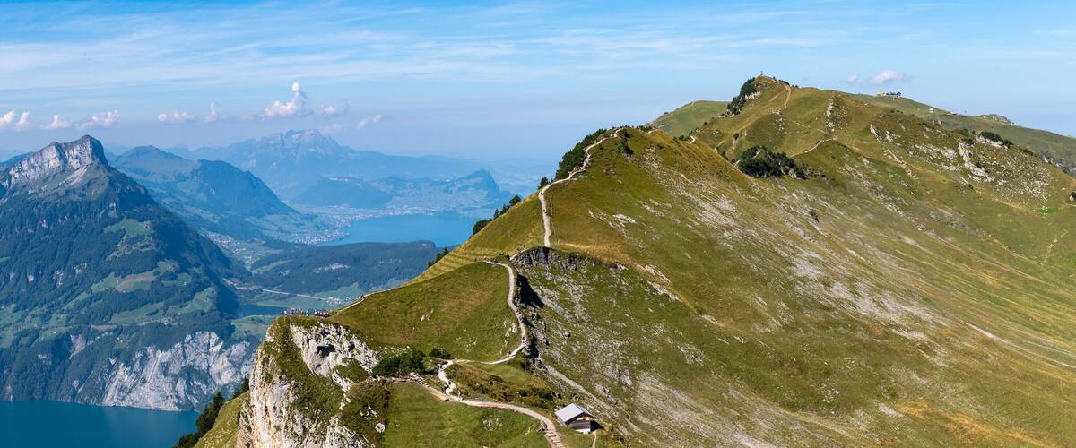 A mountain landscape with a clear sky, a lake, and a winding path.