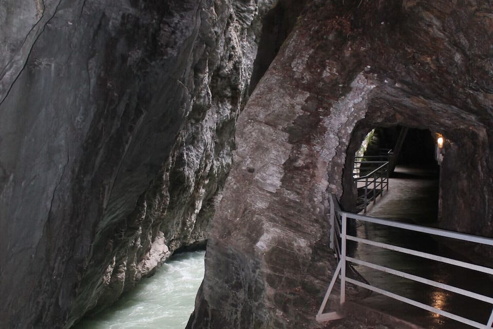 A river flowing through a rocky gorge with a tunnel entrance.