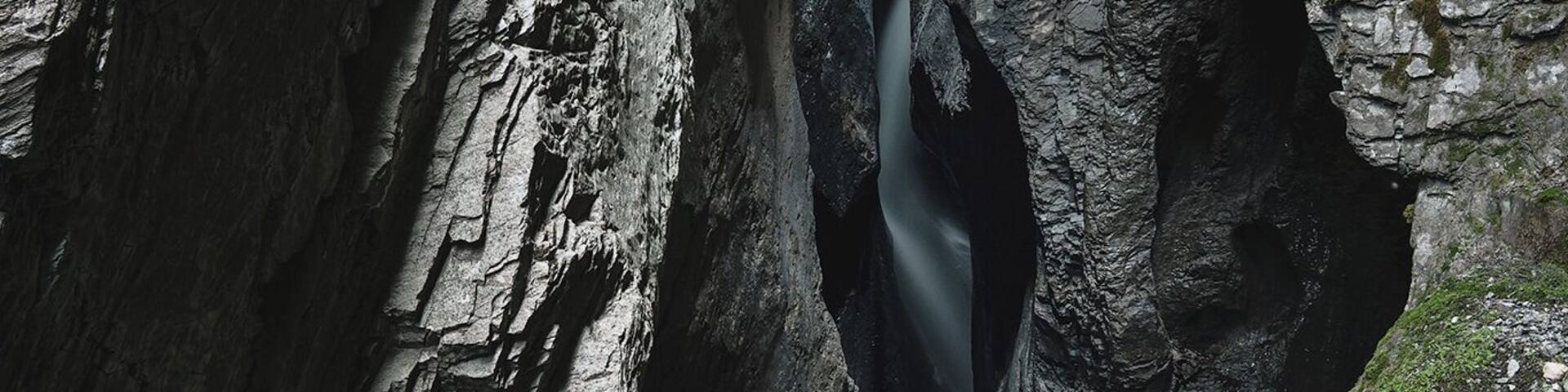 A narrow canyon with steep rock walls and a flowing stream.