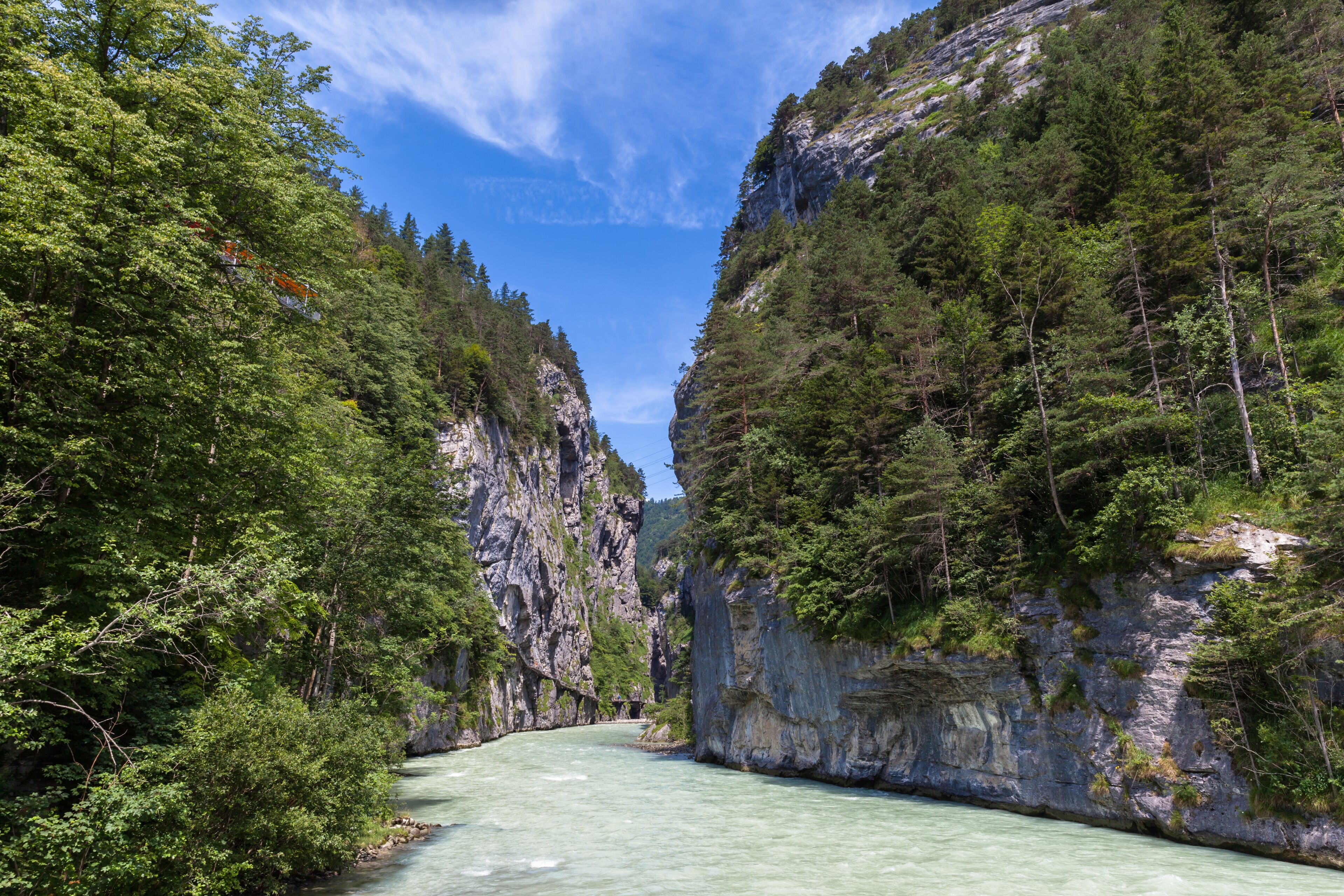 Ein Fluss fließt durch eine Schlucht, umgeben von dichtem Wald und steilen Felswänden.