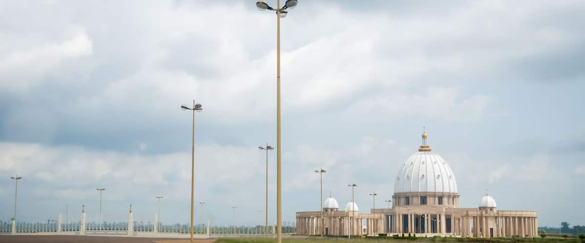 A large white building with a dome and columns, surrounded by a fence and streetlights.
