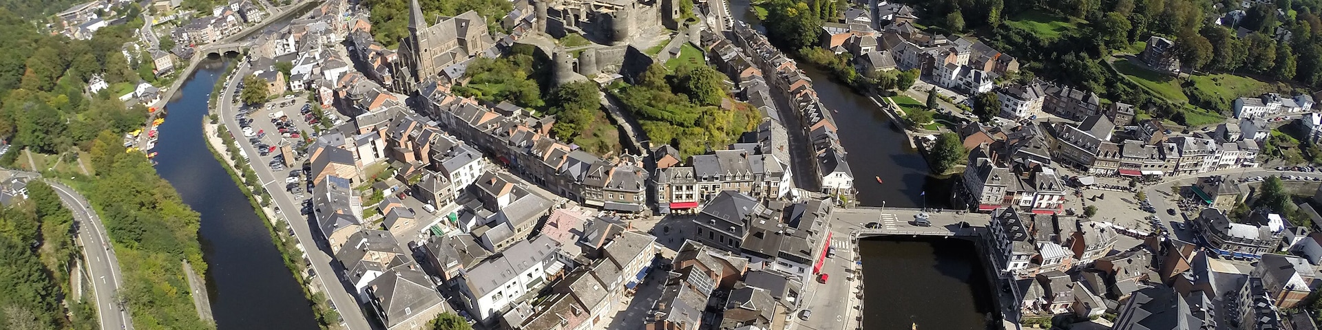 A river winding through a historic town with medieval architecture, surrounded by green hills.