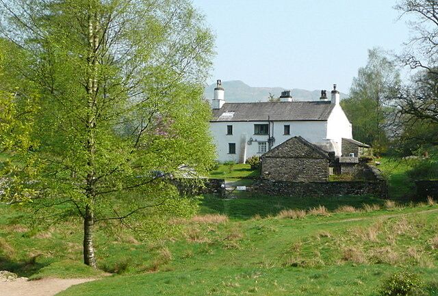 Uma casa branca com parede de pedra em ambiente rural.