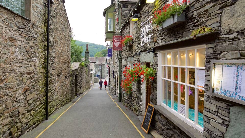 A narrow stone-paved street lined with traditional stone buildings, some with flower boxes and signage indicating a restaurant and tea rooms.