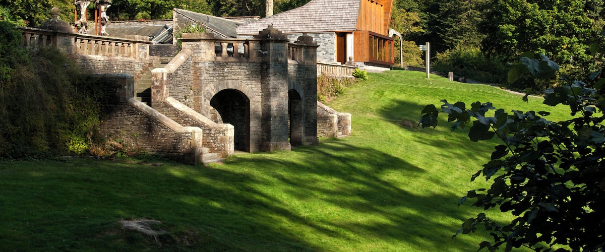 A stone bridge, a wooden building, and a lush green landscape with trees.