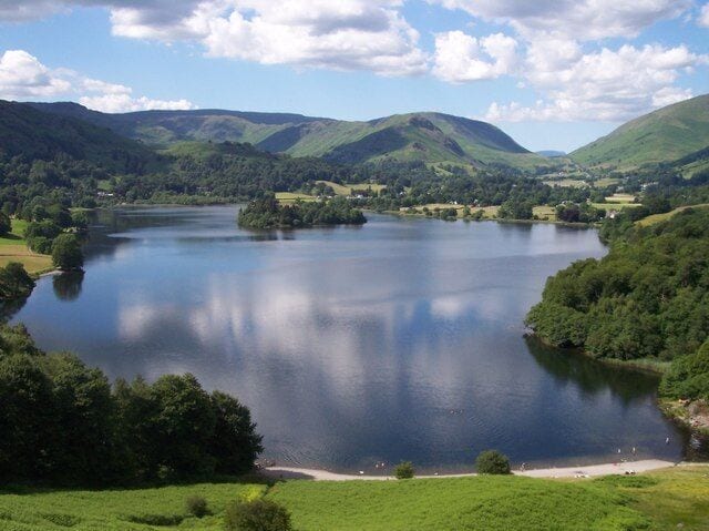 A lake surrounded by green hills and trees.