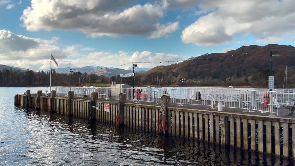 A wooden pier extending into a lake with a mountainous backdrop.