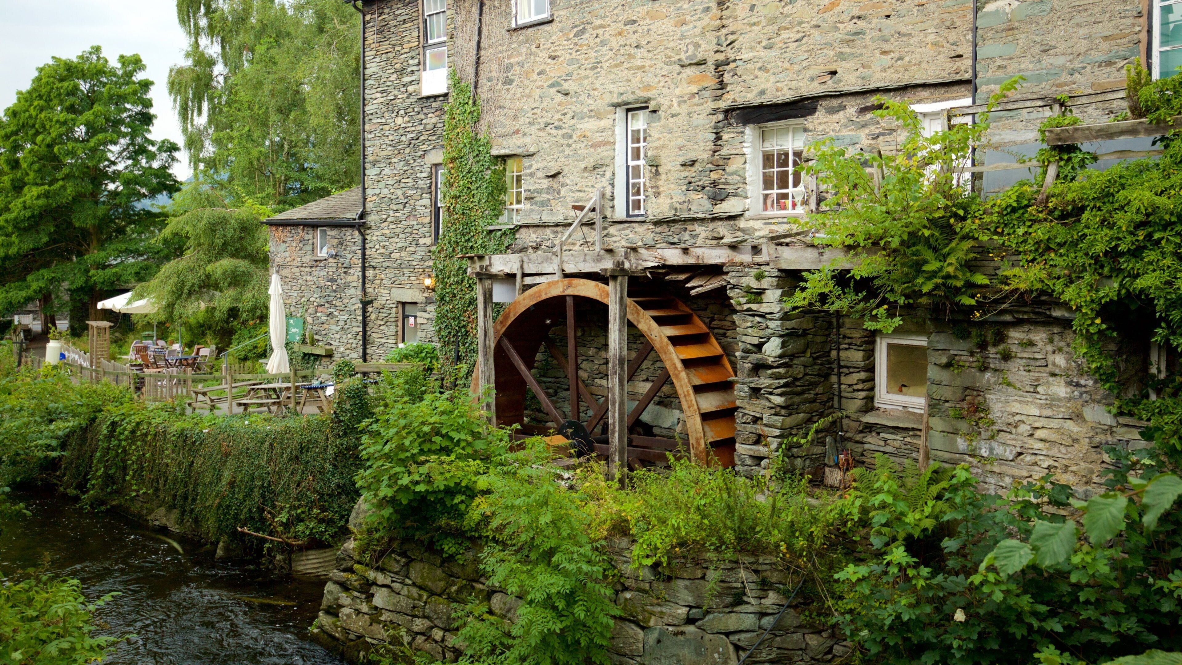 A stone building with a large water wheel and a river in front.