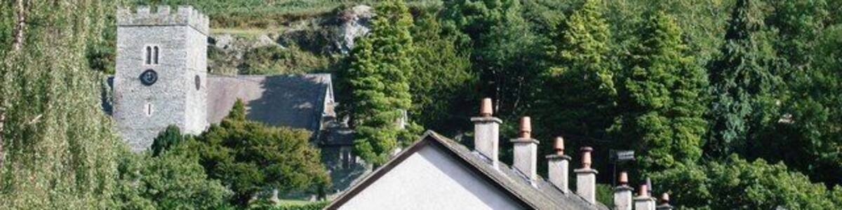 Eine gebirgige Landschaft mit felsigem Gelände, einer Kirche und einem Wohngebäude.