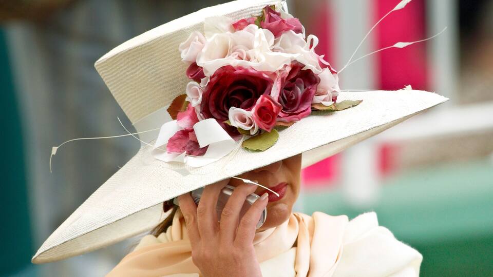 A person wearing a white hat with a floral decoration.