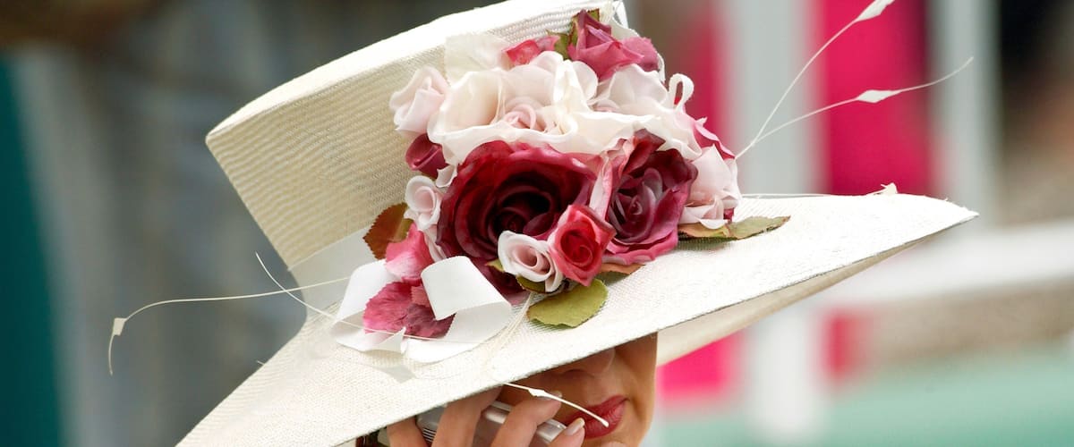 A person wearing a white hat with a floral decoration.