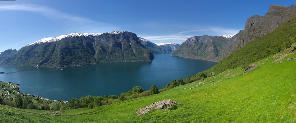 A mountainous landscape with a lake, green fields, and a road with cars.